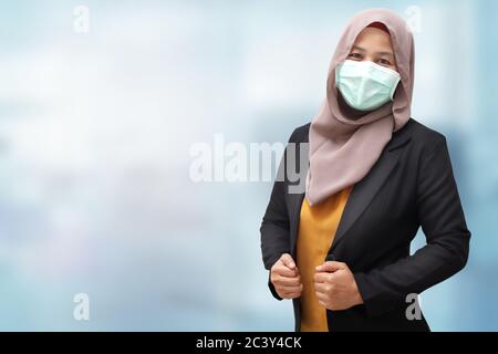 Donna d'affari musulmana asiatica che indossa suite formale e hijab durante il coronavirus covid pandemic nuova normale, donna che indossa maschera protettiva per il viso, contro bl Foto Stock