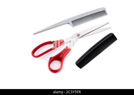 utensili per il taglio dei capelli, tra cui forbici rosse con manico e due pettini isolati su bianco Foto Stock