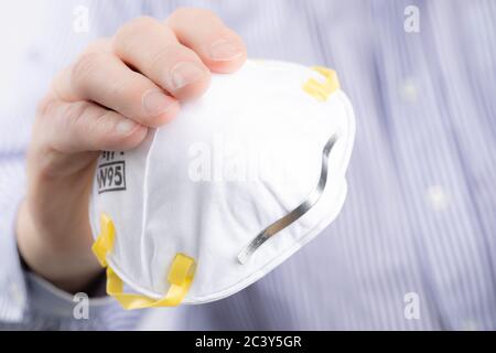 Closeup estremo di un uomo che contiene una maschera di respiratore N95 usata per la protezione da virus trasportati dall'aria come Coronavirus e covid-19 Foto Stock
