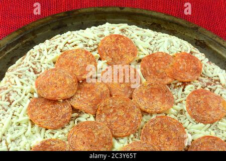 Preparazione di pepperoni surgelati e pizza al formaggio su una teglia per pizza con agenti atmosferici Foto Stock