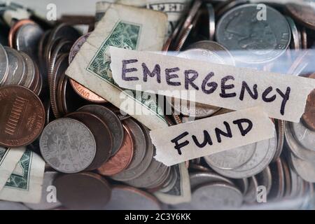 Primo piano di monete e banconote in vaso etichettato Emergency Found Foto Stock