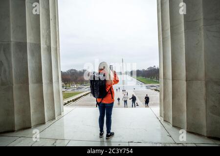 USA, Washington, Tourist scatta foto del Washington Monument attraverso lo stagno al National Mall utilizzando uno smartphone Foto Stock