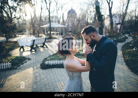 Sposo baciando le mani della sua moglie appena sposata in giardino Foto Stock