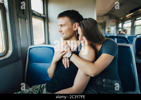 Giovane coppia che si abbraccia in treno Foto Stock