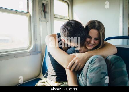 Giovane coppia che si abbraccia in treno Foto Stock