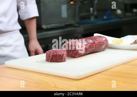 Grande bistecca di manzo disossata grezza tagliata su un tagliere bianco. Ingredienti di carne freschi pronti per cucinare. Foto Stock