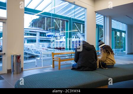 Milford Sound, Fiordland, Nuova Zelanda, giugno 19 2020: Due turisti neozelandesi nel terminal dei traghetti di Milford Sound, in attesa di fare una crociera Foto Stock