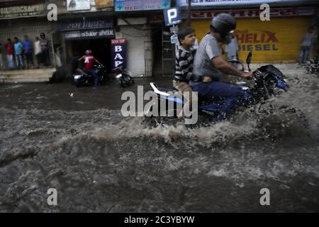 Gli automobilisti che attraversano una strada allagata sotto una forte pioggia a Jaipur, Rajasthan, India. Foto Stock