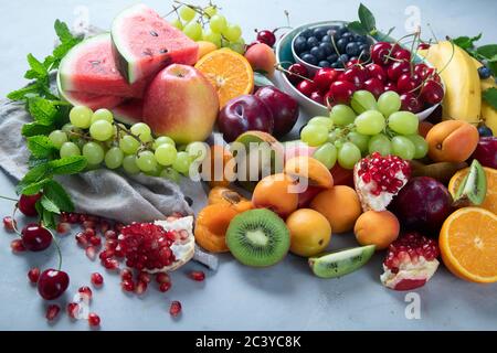 Frutta fresca e sana su sfondo grigio. Alimenti ad alto contenuto di antiossidanti, carboidrati, minerali e vitamine. Cibo per il potenziamento immunitario. Foto Stock