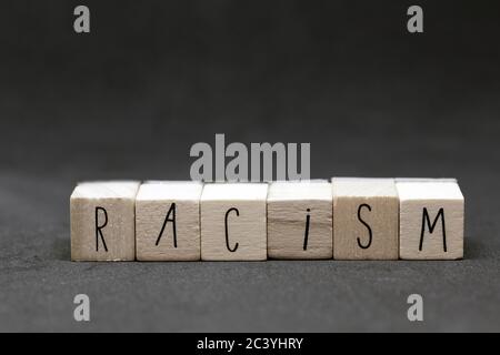 Cubi di legno con la parola razzismo su sfondo scuro, nero vive materia concetto Foto Stock