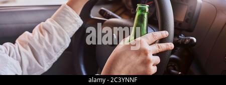 Una birra femminile non riconoscibile mentre si guida in auto. Concetti di guida sotto l'influenza, guida ubriaca o guida compromessa Foto Stock
