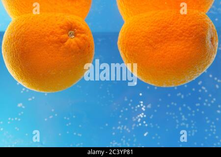 Frutta fresca che cade in arance d'acqua su sfondo blu Foto Stock
