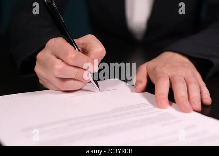 Donna firma un contratto, primo piano di mani con penna su carta Foto Stock