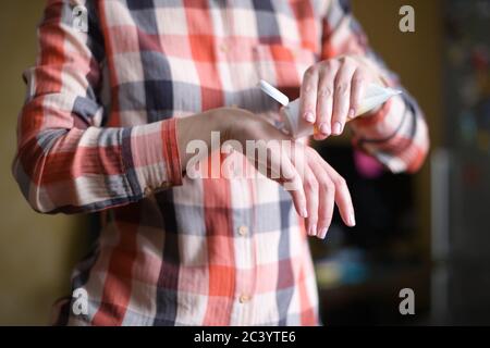 la ragazza stringe una piccola quantità di crema e strofina per le mani esso sulle mani Foto Stock