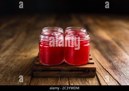 Tiratori alcolici di colore rosso, o bevande sparate su un tavolo di legno Foto Stock