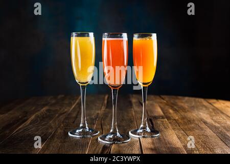 Tre diversi cocktail frizzanti, rossi, gialli e arancioni, in calici di flauto Foto Stock