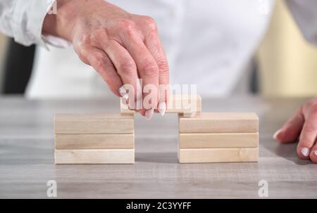 Mano femmina costruzione di un ponte con blocchi di legno; concetto di associazione Foto Stock