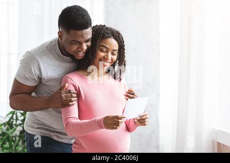 Donna incinta e suo marito che guarda l'immagine Foto Stock