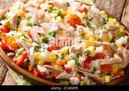 Insalata estiva di riso, tonno e verdure fresche primo piano in un piatto sul tavolo. Orizzontale Foto Stock