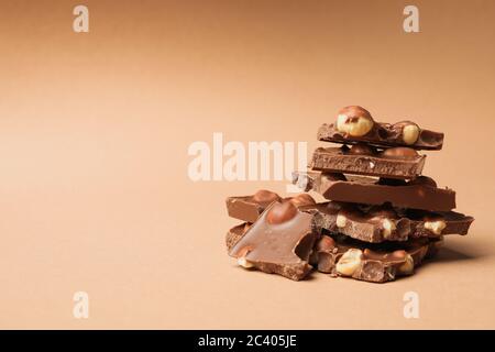 Pezzi di cioccolato su sfondo beige. Cibo dolce Foto Stock