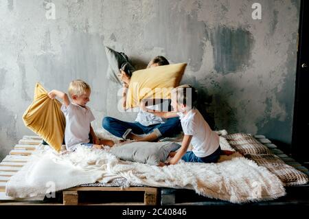 Tempo di gioco per la famiglia. Mamma e figli scherzano e combattono cuscini. Ventilatore di famiglia. Foto Stock