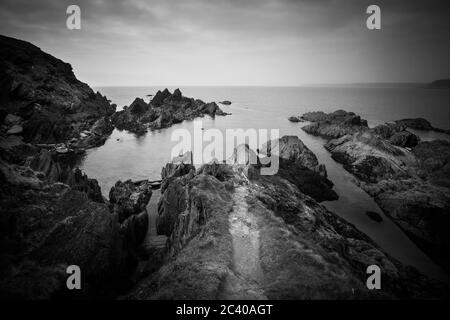 Burgh Island, Devon, Regno Unito. 21 marzo 2016. Il mare si affaccia su rocce ai margini dell'isola. Foto Stock