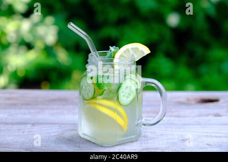 Disintossicare l'acqua di frutta infusa con cetriolo, limone e menta in un vaso di vetro con cannuccia. Cocktail estivo fatto in casa Foto Stock