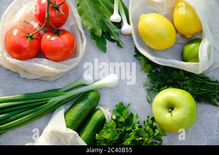 Concetto di shopping senza sprechi. Verdure fresche e frutta in sacchetti di cotone eco-friendly su tavola di pietra. Vista dall'alto, pomodori a piatto, cetrioli, limoni, gr Foto Stock