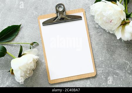 Composizione di nozze in stile piatto con appunti in foglio bianco mockup e fiori di pony su tavola di pietra. Vista dall'alto. Foto Stock