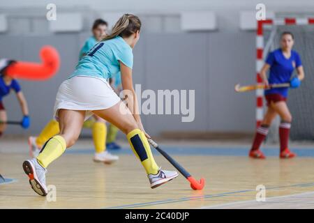 Giovane giocatore di hockey al coperto con la palla in attacco. Foto Stock