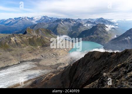 Sicht vom Bättelmatthorn auf der Grenze Italien-Wallis hinunter zum Griessee mit der Windenergieanlage und zur Passhöhe des Nufenenpasses mit der Pass Foto Stock