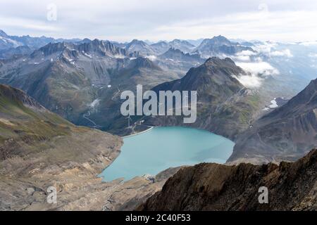 Sicht vom Bättelmatthorn auf der Grenze Italien-Wallis hinunter zum Griessee mit der Windenergieanlage und zur Passhöhe des Nufenenpasses mit der Pass Foto Stock