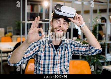 Business, persone, visione 3d e concetto di successo. Uomo d'affari sorridente e portatore di un sorriso in una camicia casual a scacchi, divertente mentre prova la nuova realtà virtuale 3d Foto Stock