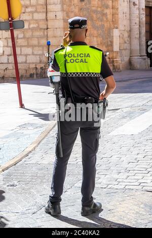 Vista posteriore della polizia spagnola con il logo 'polizia locale' emblema su uniforme mantenere l'ordine pubblico nelle strade di Jaen, Spagna Foto Stock