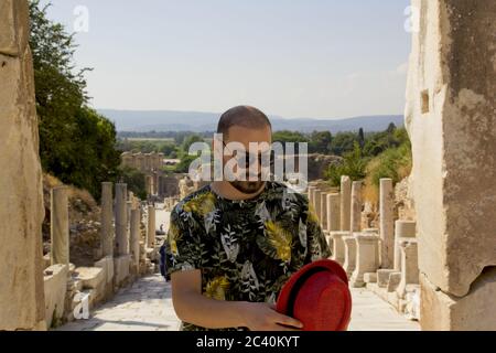 Bel giovane in cappello rosso nell'antica città di Efeso Foto Stock