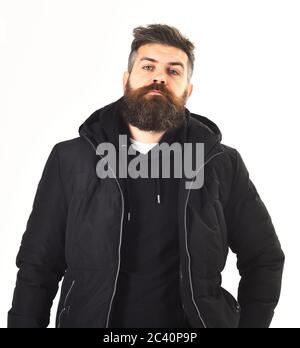Il ragazzo indossa abiti neri e brutali. L'uomo con il viso calmo indossa abiti caldi, isolati su sfondo bianco. Macho con barba e baffi provare su cappotto invernale. Abbigliamento invernale e abbigliamento maschile. Foto Stock