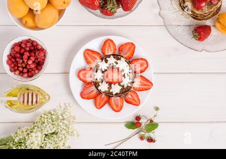 Una ricetta passo-passo per decorare frittelle per una colazione per bambini sotto forma di sole da vicino con fragole e panna montata. Fase 2 - A. Foto Stock