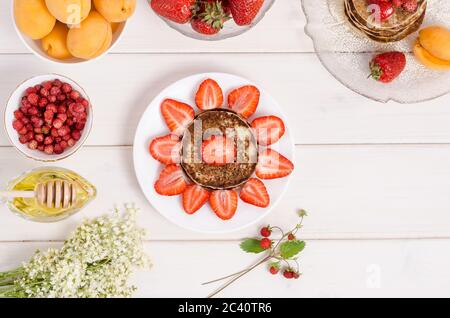 Una ricetta passo-passo per decorare frittelle per una colazione per bambini sotto forma di sole da vicino con fragole e panna montata. Fase 1- ch Foto Stock