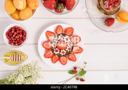 Una ricetta passo-passo per decorare frittelle per una colazione per bambini sotto forma di sole da vicino con fragole e panna montata. Fase 3- ga Foto Stock