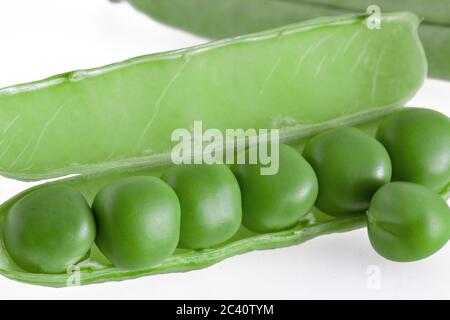 piselli freschi si trovano in un baccello aperto. Isolato su sfondo bianco Foto Stock