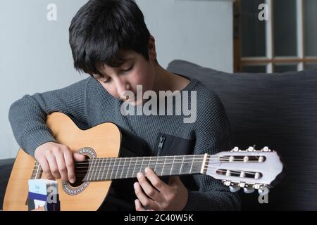 Teenage boy, 12-13 anni suona la chitarra acustica Foto Stock