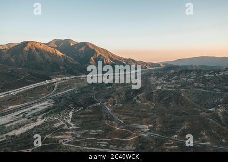 Vista aerea sulle montagne del deserto della California, con autostrada e traffico in auto Foto Stock