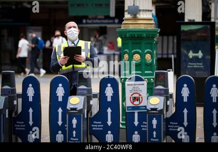 Un membro del personale indossa una maschera protettiva all'interno della Waverley Station, Edimburgo, mentre la Scozia si sposta nella seconda fase del suo piano in quattro fasi per uscire dal blocco. Foto Stock