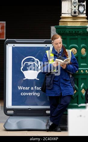 Un membro del personale indossa uno scudo protettivo all'interno della Waverley Station, Edimburgo, mentre la Scozia si sposta nella seconda fase del suo piano in quattro fasi per uscire dal blocco. Foto Stock