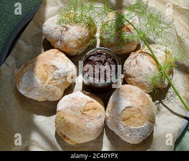 Rotoli di pasta di origine fatti in casa. Panini fatti a mano su carta da forno. Appena fuori dal forno e ancora caldo. Servito con una tapenade di pasta d'oliva. Foto Stock