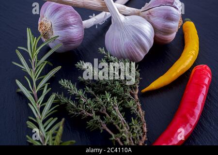 Aglio, rosmarino, timo e peperoncini su un piatto di ardesia Foto Stock