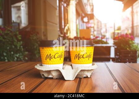 Lviv, Ucraina - 17 maggio 2020 : Ristorante McDonalds nel centro della città, due tazze di caffè dal McCafe su tavolo di legno contro la città di sfondo presto Foto Stock
