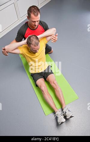 Personal trainer aiutando client in palestra Foto Stock