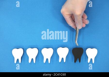 Decadimento dei denti e concetto di assistenza sanitaria dentale. Mano dentista con pinzette che tira i denti neri. Foto Stock