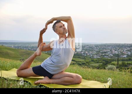 Un uomo pratica yoga meditazione equilibrio in natura. Foto Stock